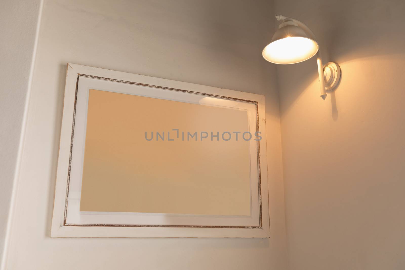 Modern wall frame fixed on the wall under a wall lamp at home