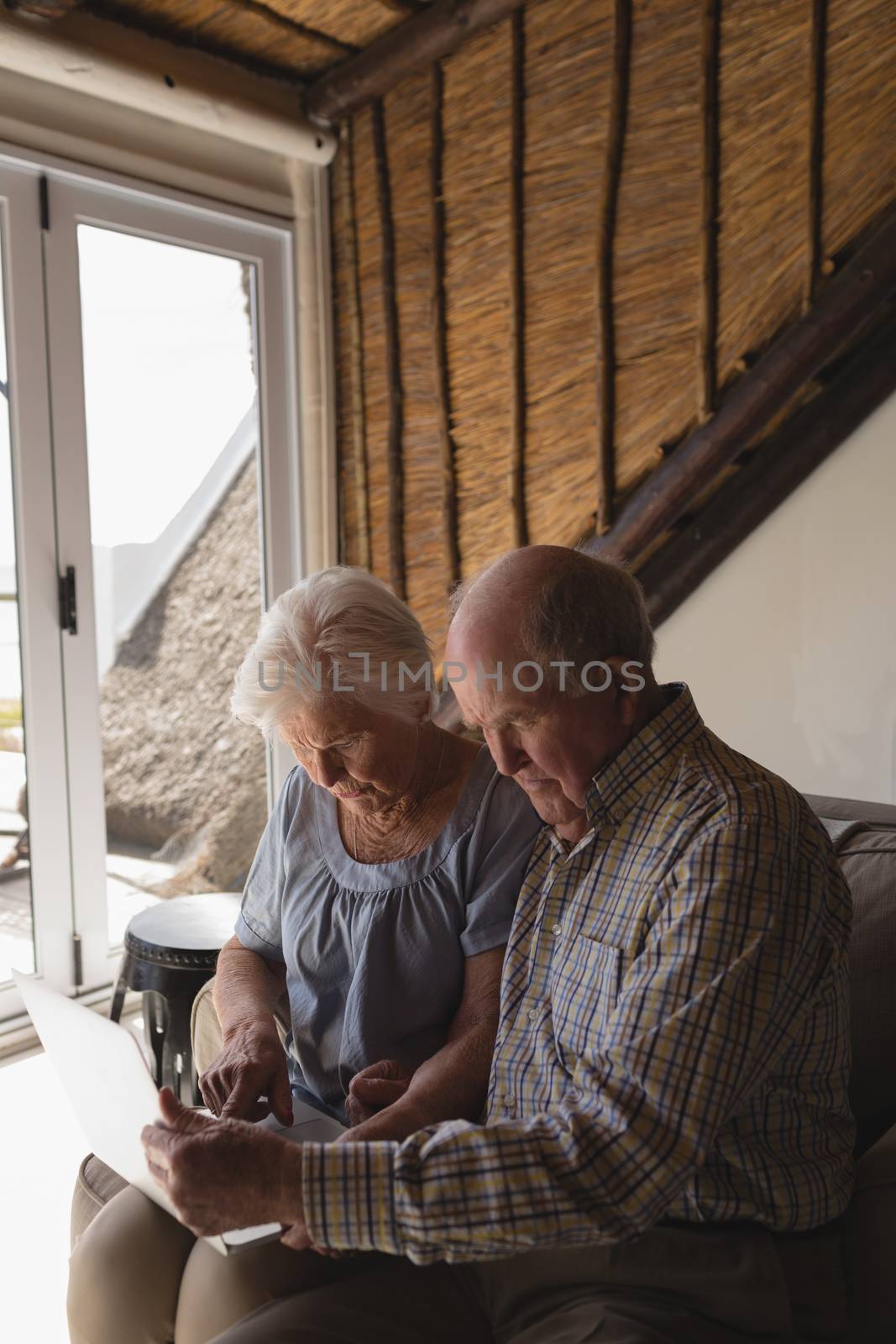 Side view of a senior couple using laptop on a sofa in living room at home