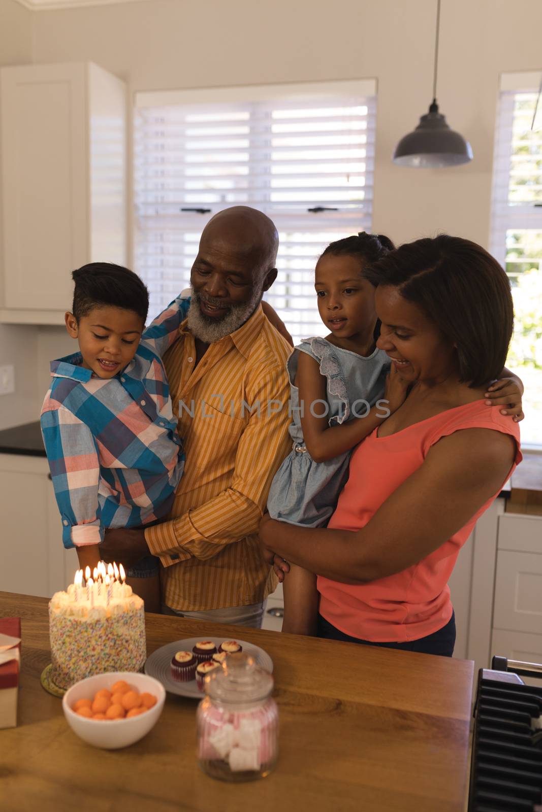 Front view of a happy African American multi-generation family celebrating birthday with fire candles on the birthday cake at home