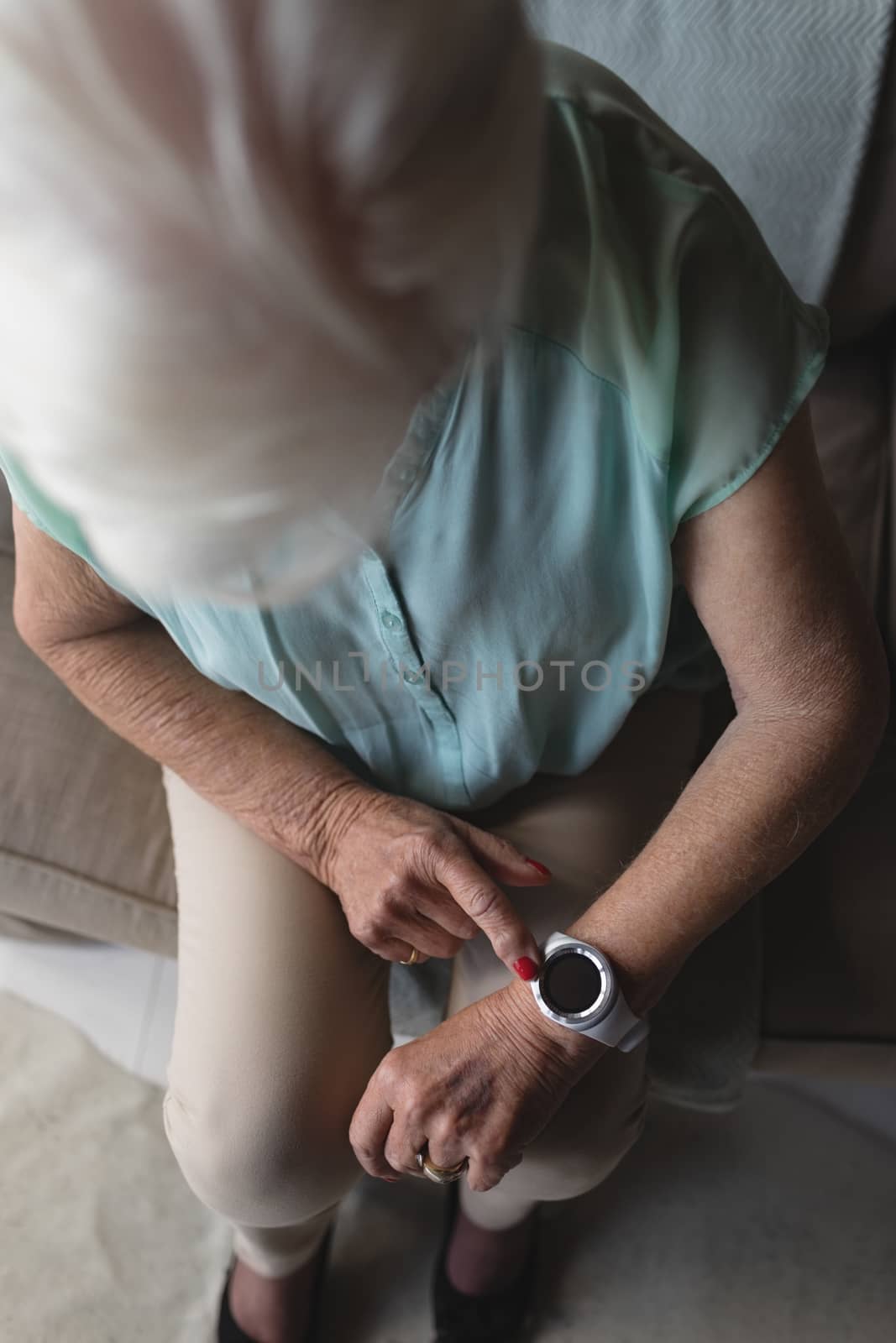 High angle view of a senior woman checking time on her wristwatch at home