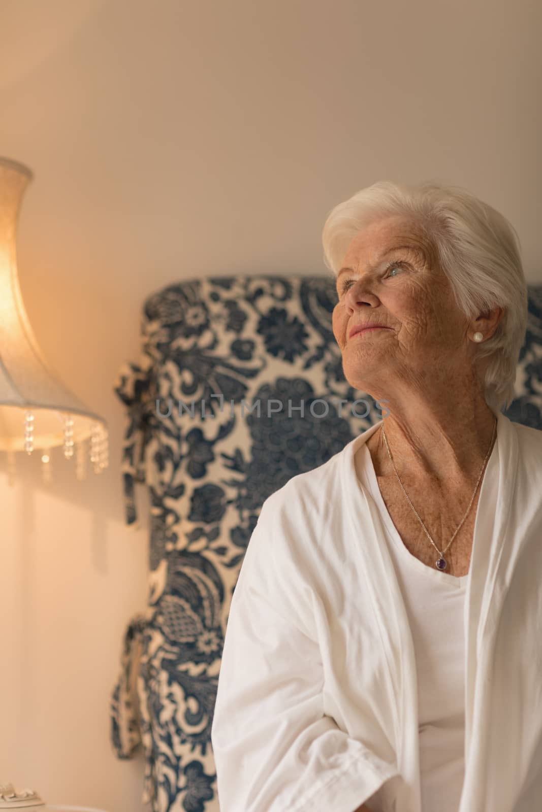 Front view of a senior woman looking up in her bedroom at home