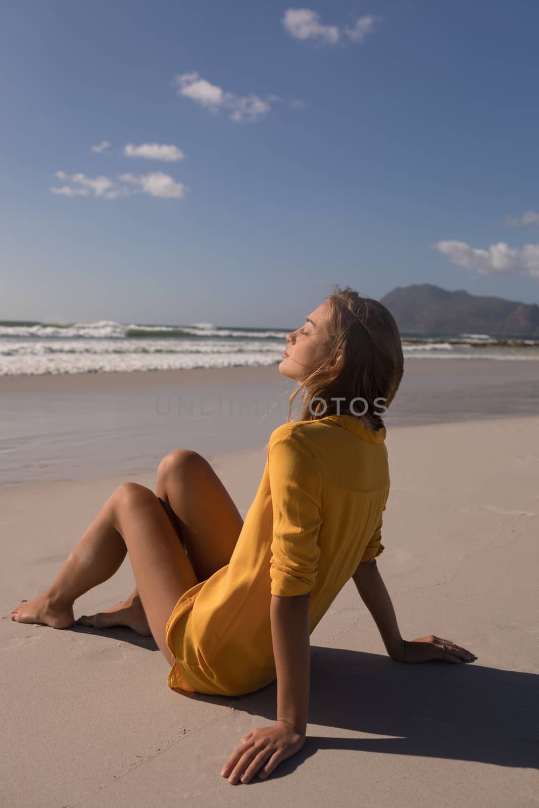 Side view of beautiful woman relaxing with eyes closed at beach on a sunny day