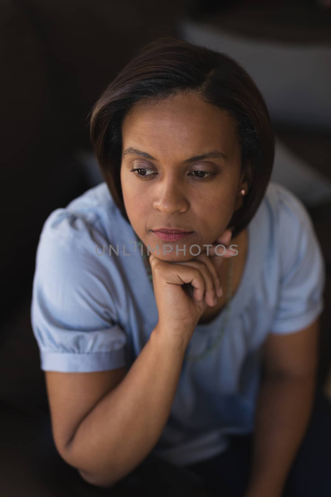 High angle view of thoughtful woman relaxing on sofa in living room at home
