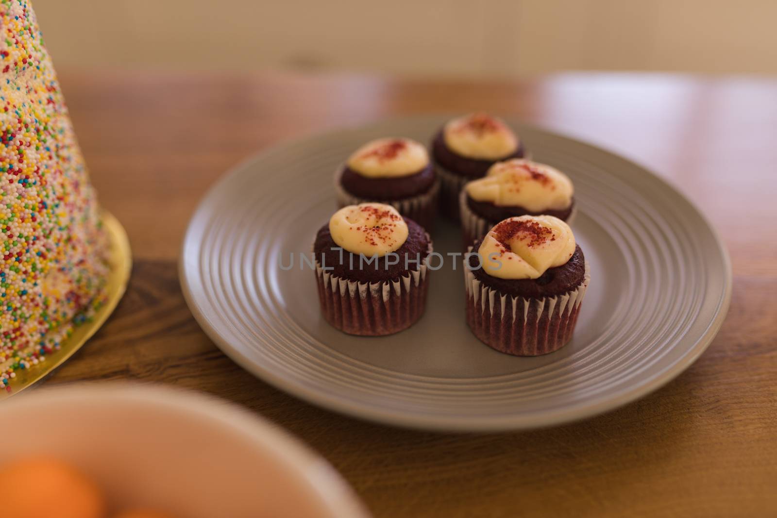 Close-up of chocolate cupcakes with topping on a plate on a wooden table at home