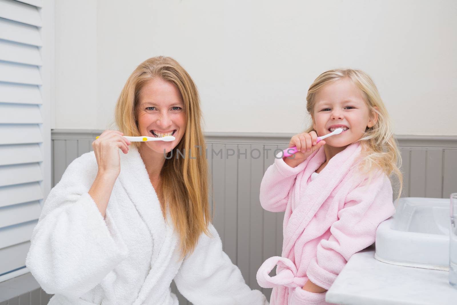 Happy mother and daughter brushing their teeth by Wavebreakmedia