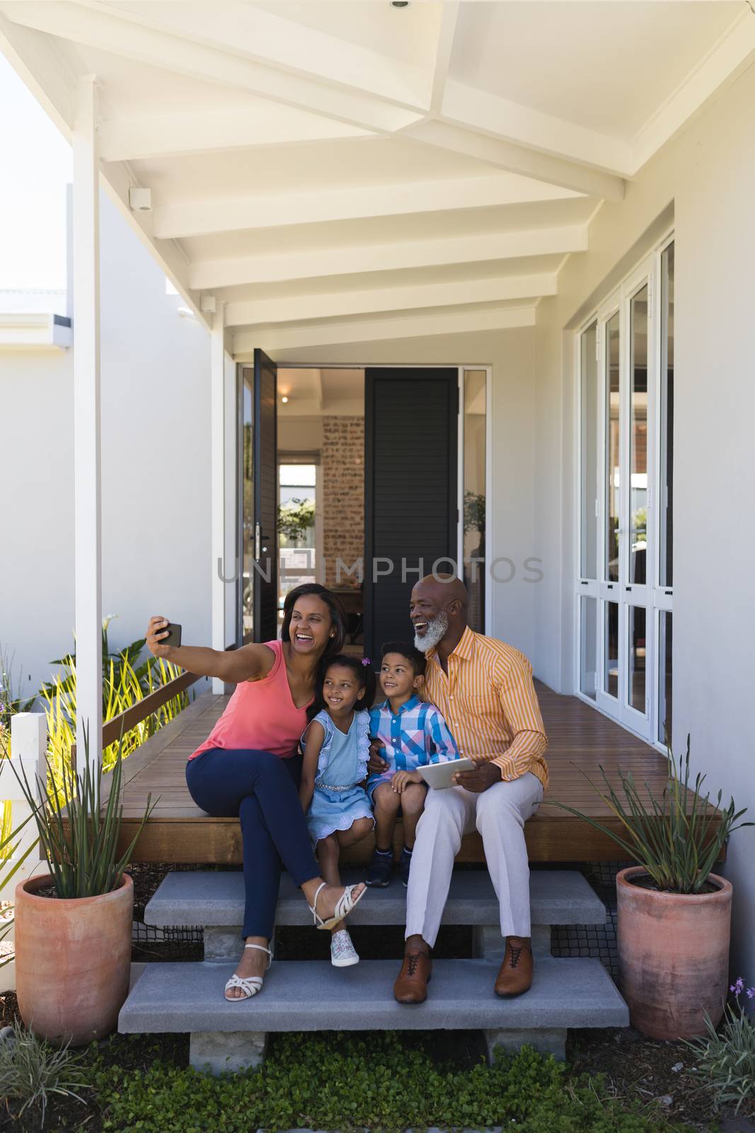 Multi-generation family taking selfie with mobile phone in the porch by Wavebreakmedia