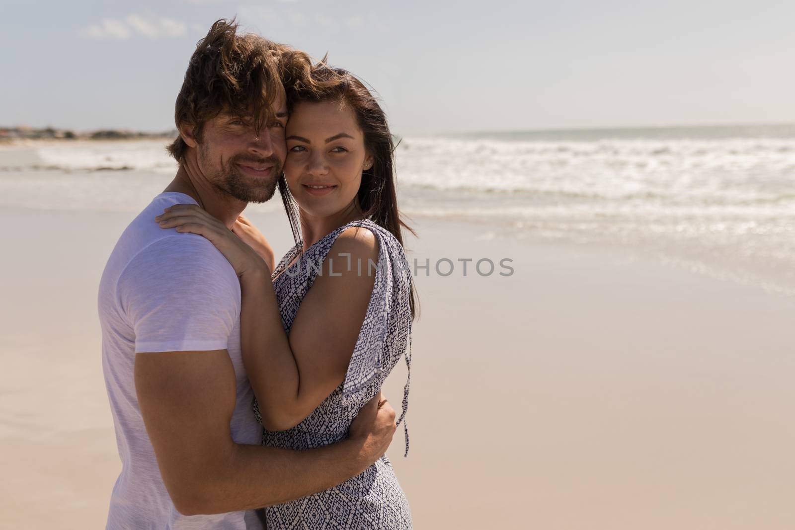 Romantic happy young couple embracing on beach by Wavebreakmedia