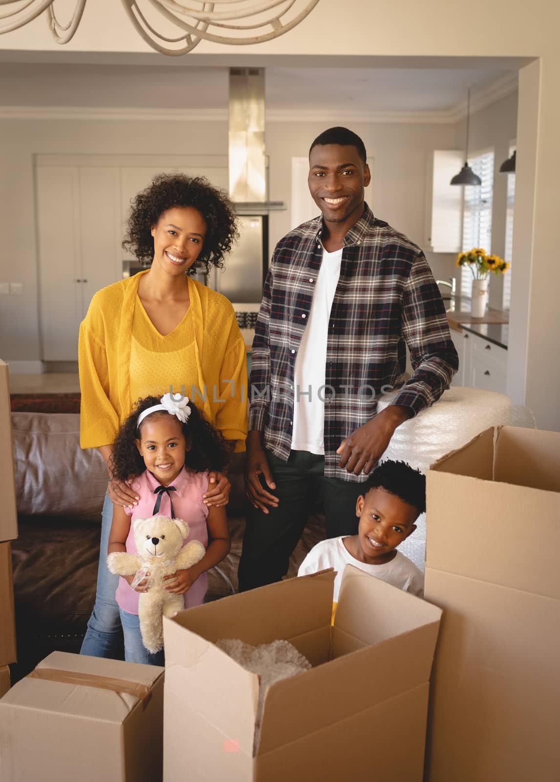 Happy African American family with cardboard boxes looking at camera in living room by Wavebreakmedia
