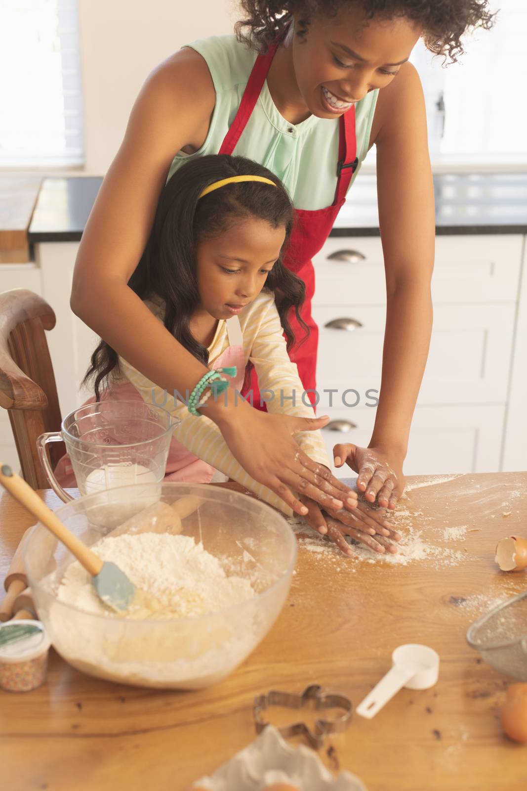 African American mother and daughter kneading dough in kitchen by Wavebreakmedia