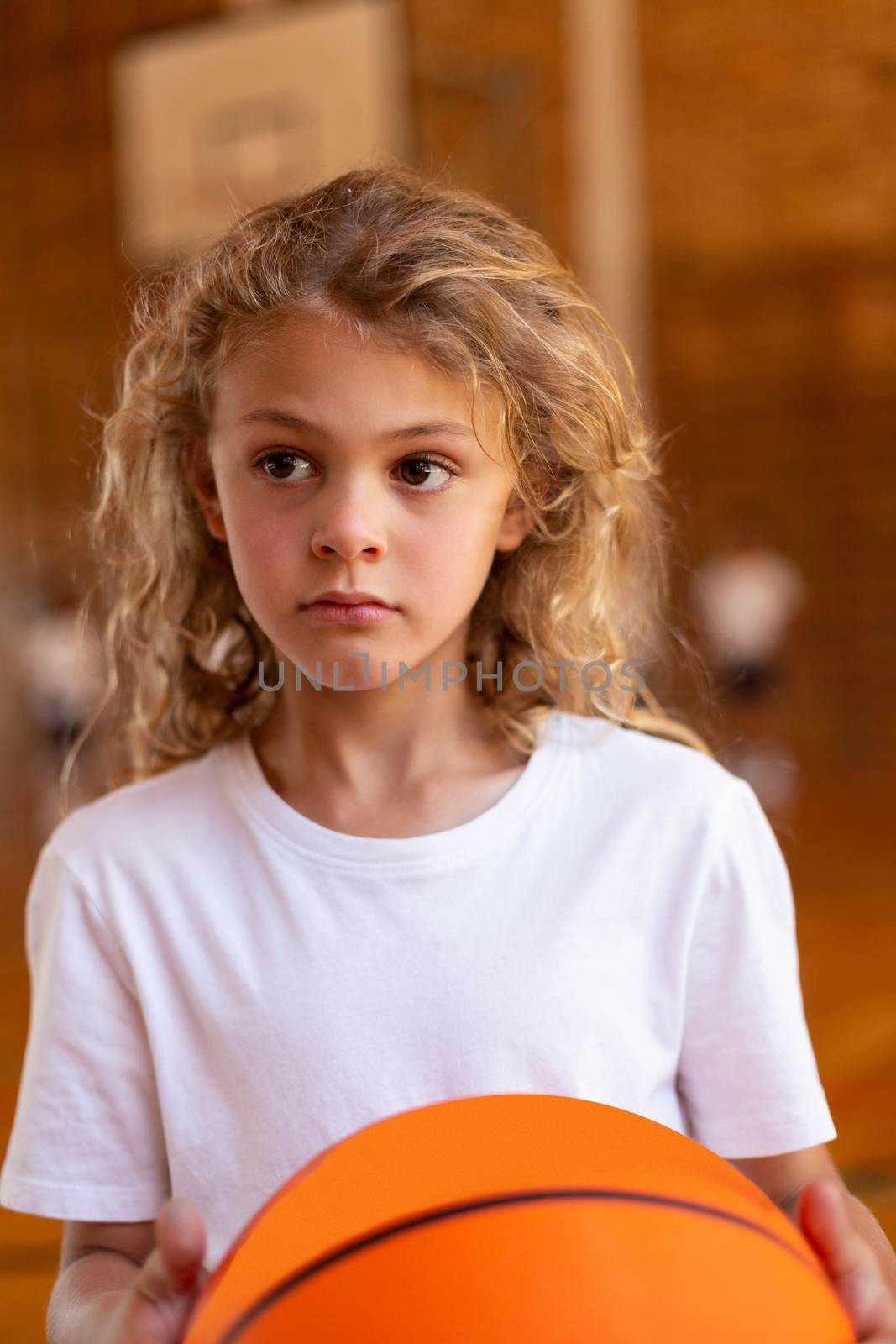 Schoolgirl with a basketball standing in basketball court by Wavebreakmedia