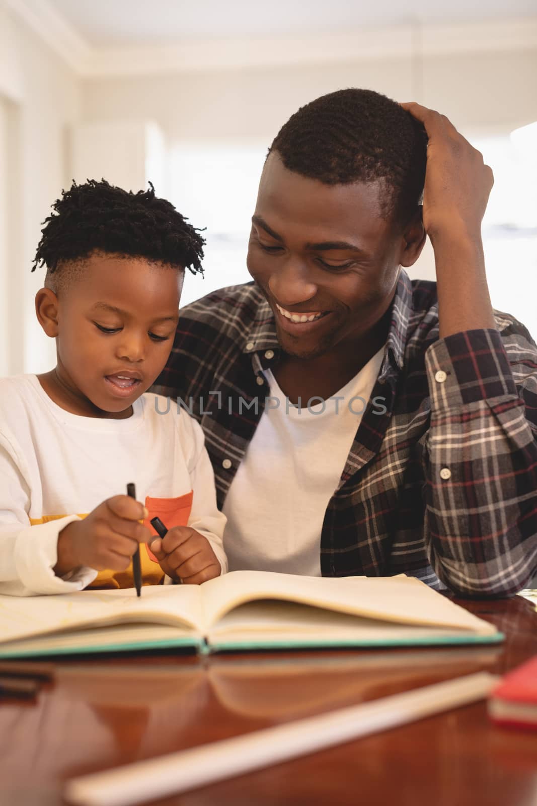 African American father helping his son with homework at table by Wavebreakmedia