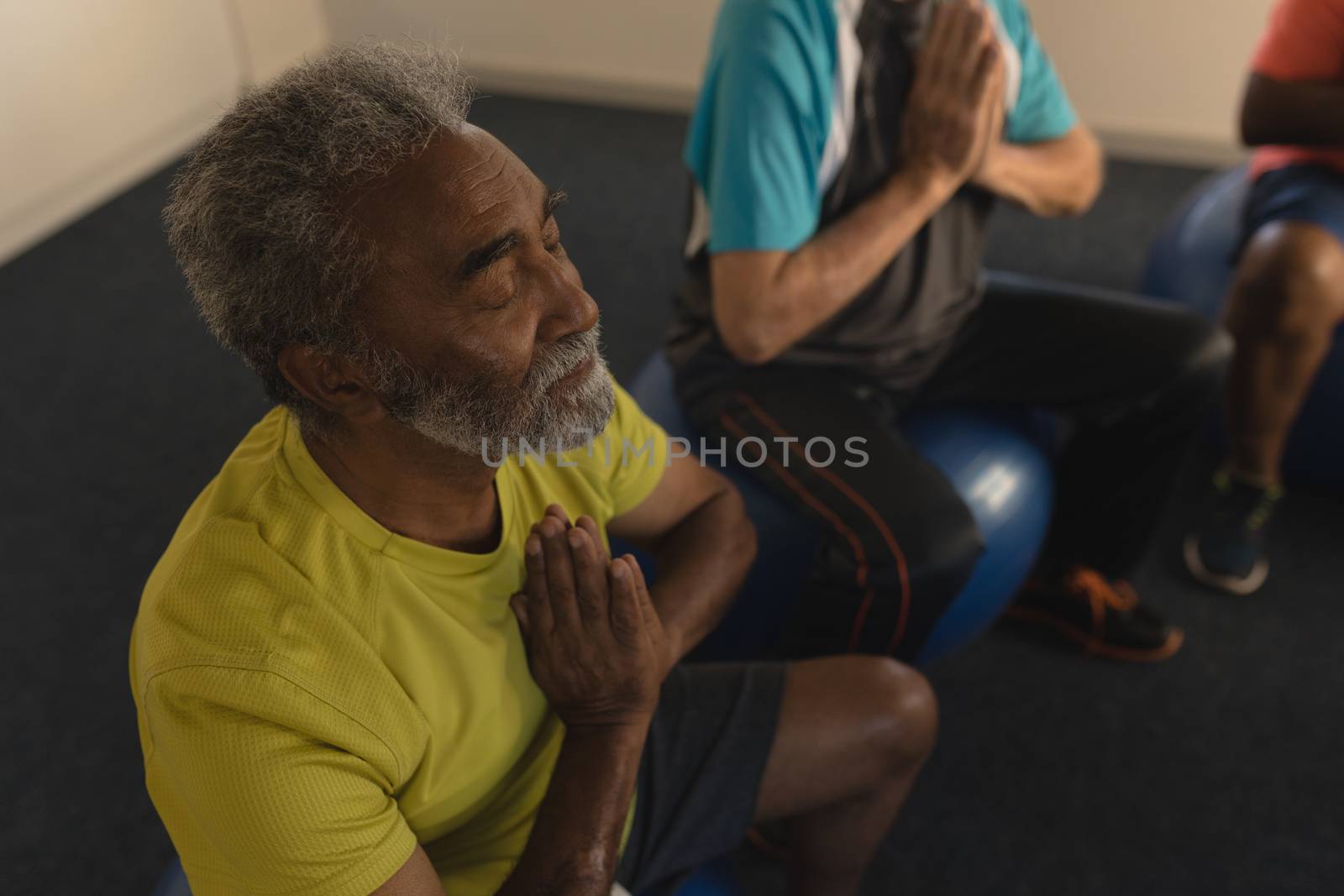 High angle view of active senior men performing yoga doing exercice ball at home