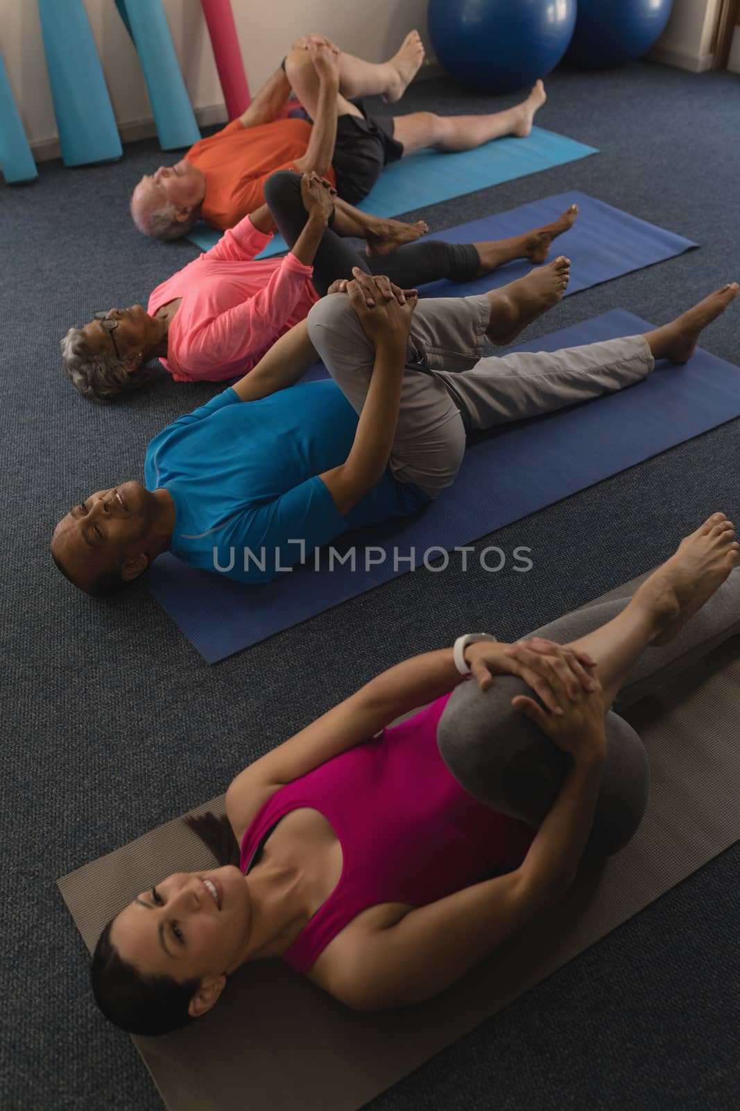 High angle view of young female trainer exercising with senior people in fitness studio