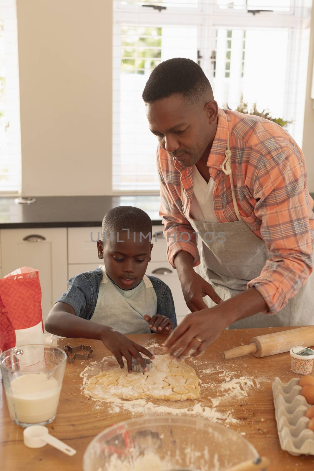 Front view of African American father and son baking cookies in kitchen at home