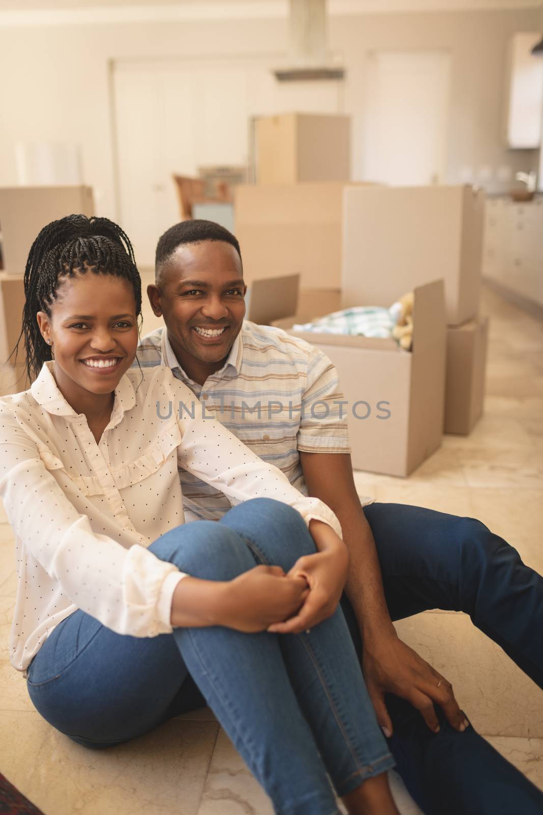 Happy African American couple sitting on floor and looking at camera by Wavebreakmedia