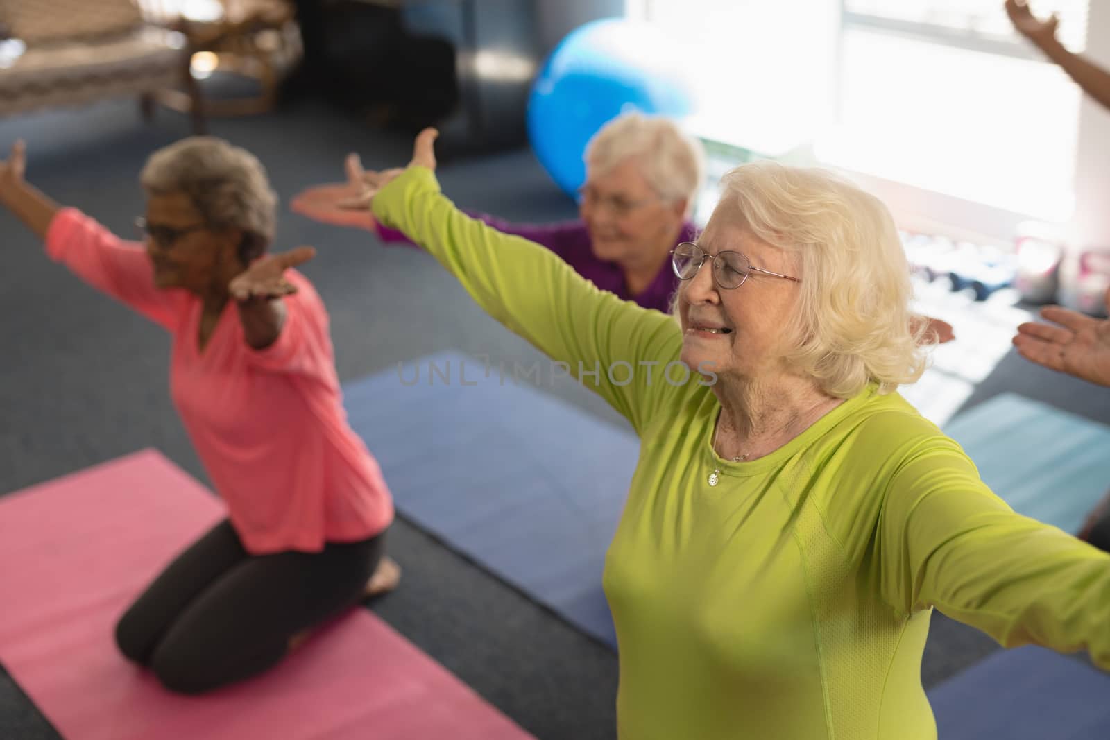 Happy senior people exercising in yoga position in fitness studio