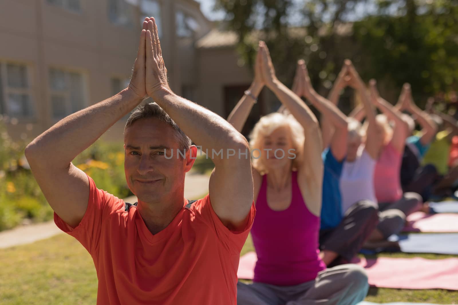 Trainer training senior people in performing yoga by Wavebreakmedia