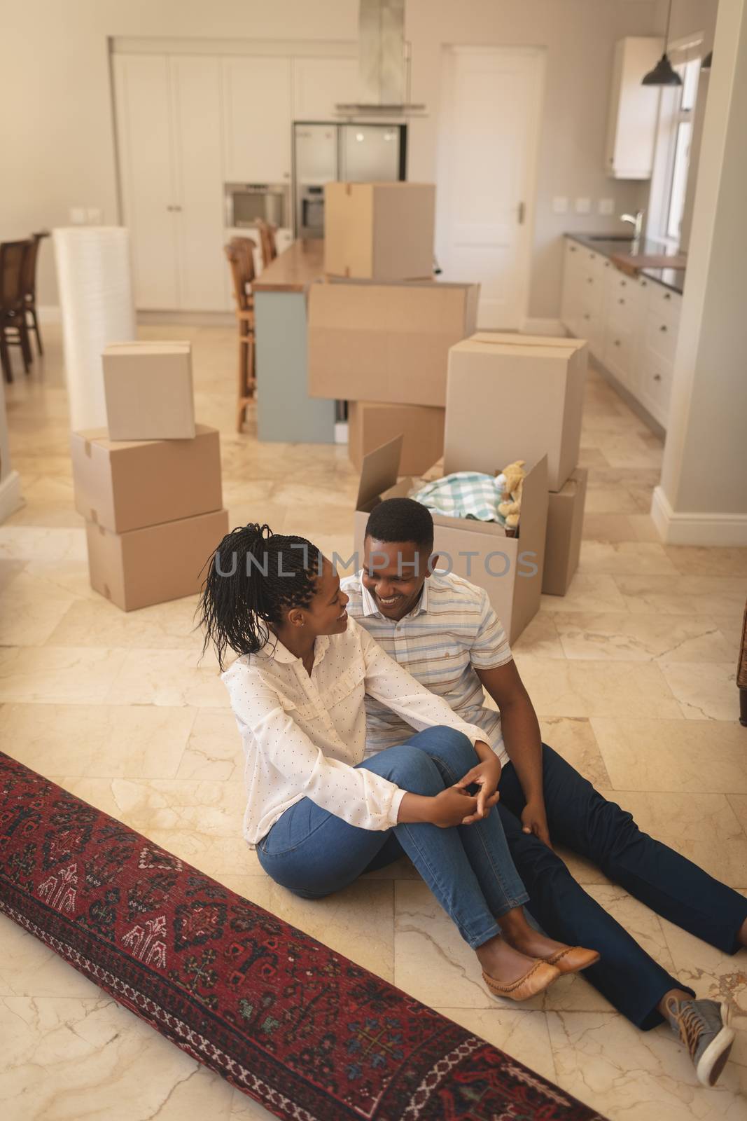 Happy African American couple sitting on floor and talking with each other by Wavebreakmedia