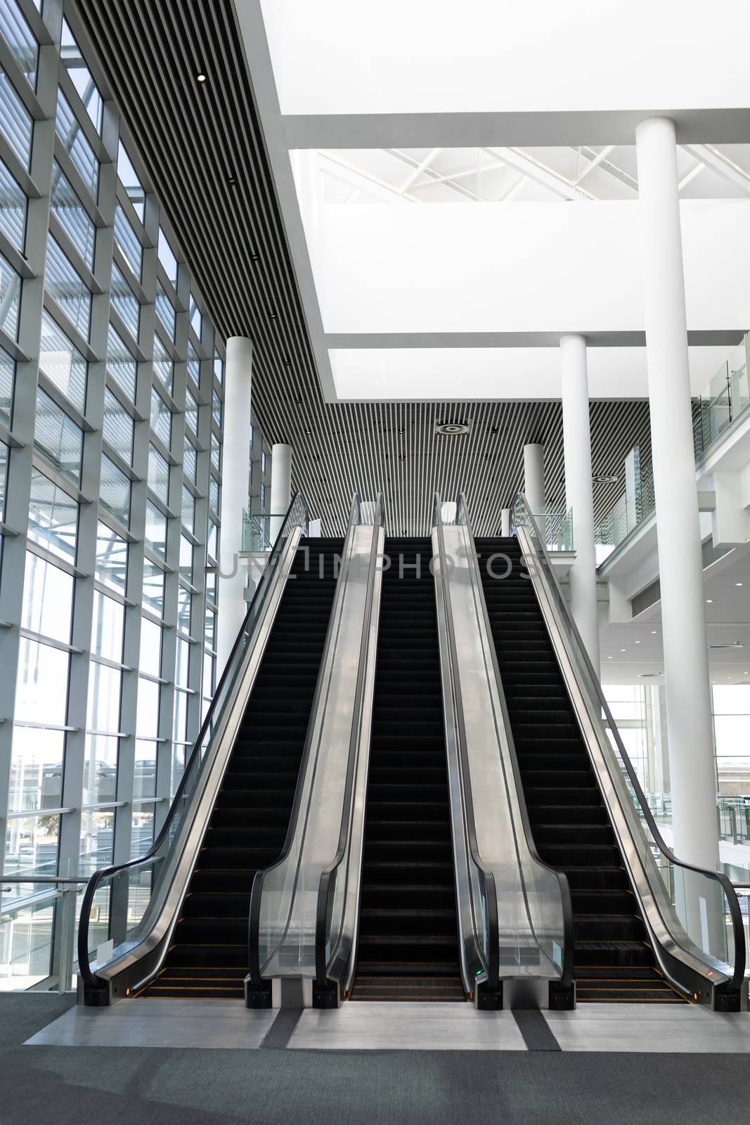 Front view of three modern escalators in a office lobby against inside buildings in background