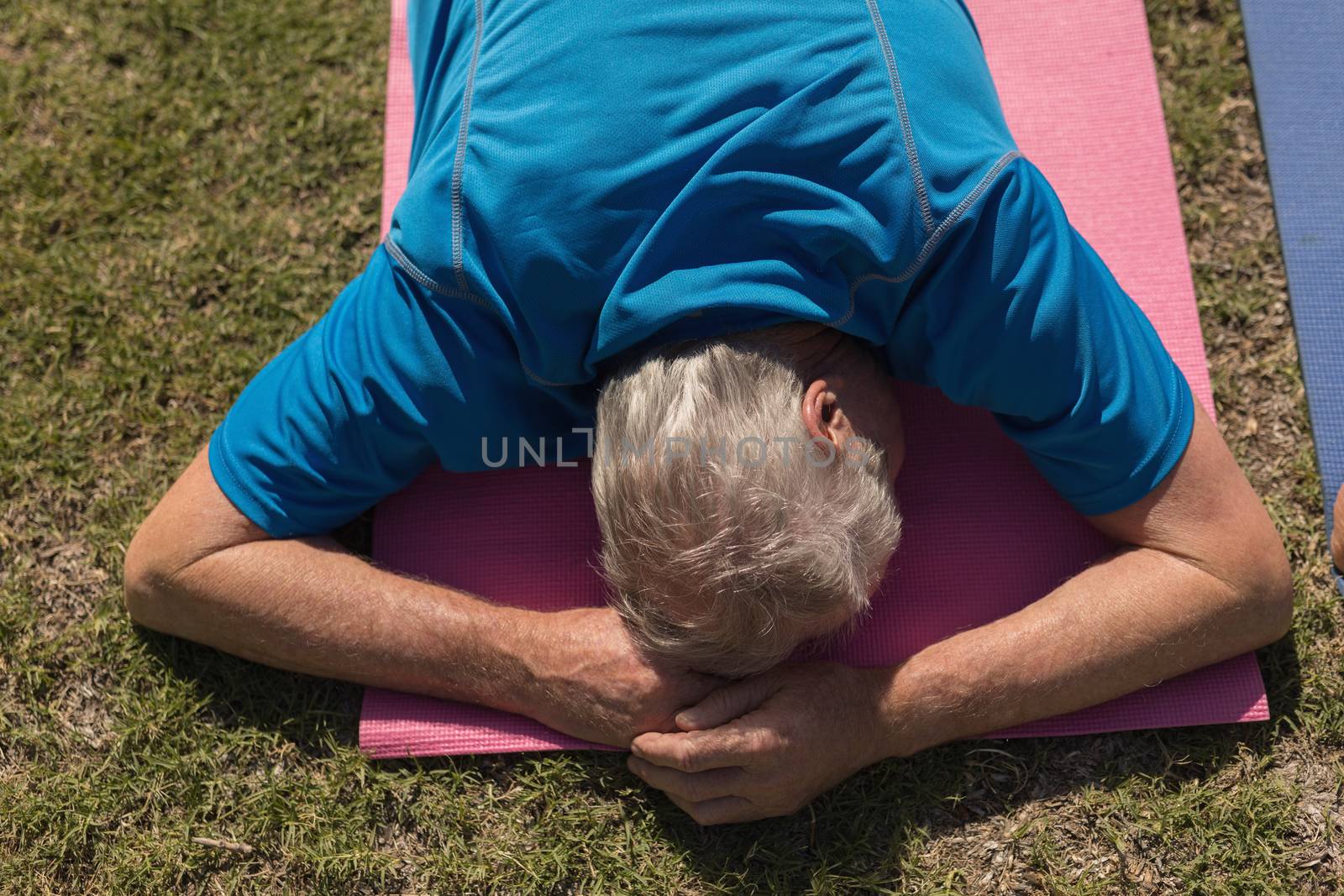 High angle view of active senior man performing yoga on his stomach on yoga mat in the park