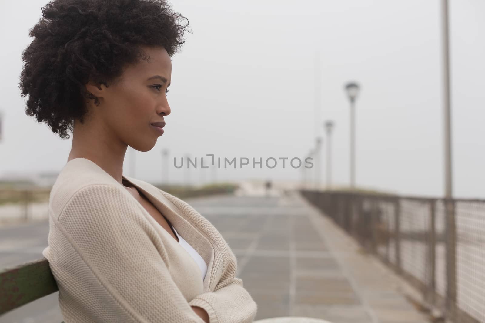 Side view of thoughtful young African American woman sitting on bench at promenade 