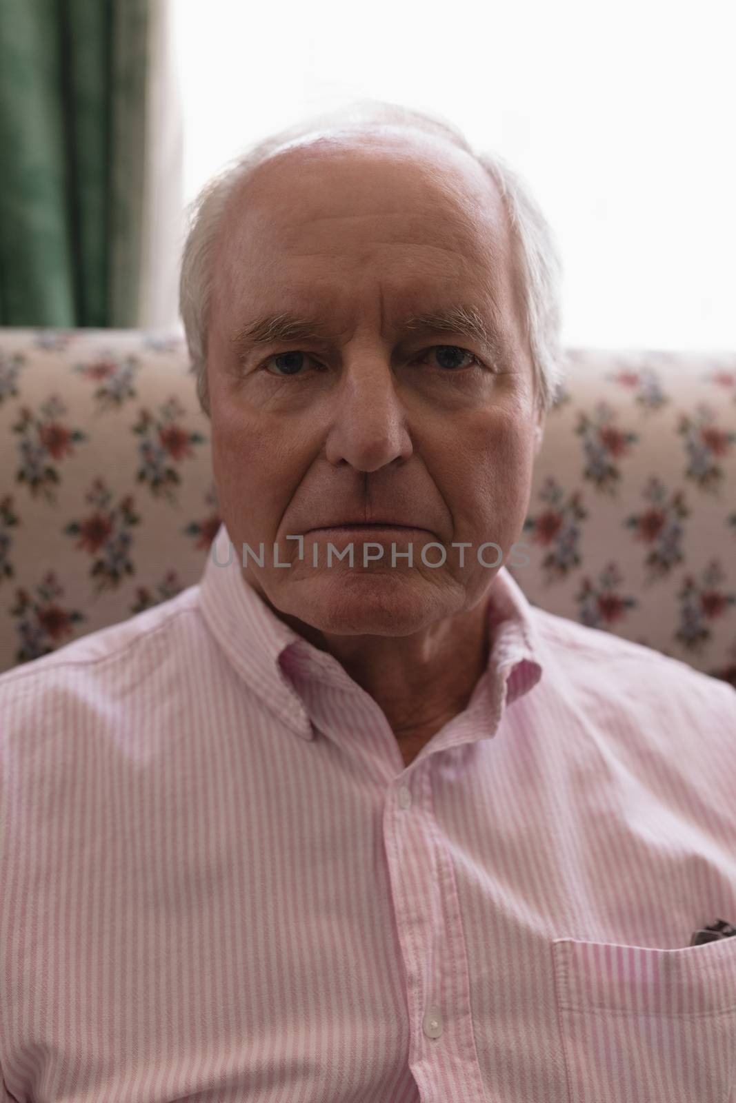Close up of active senior man relaxing in living room sitting on the sofa at home