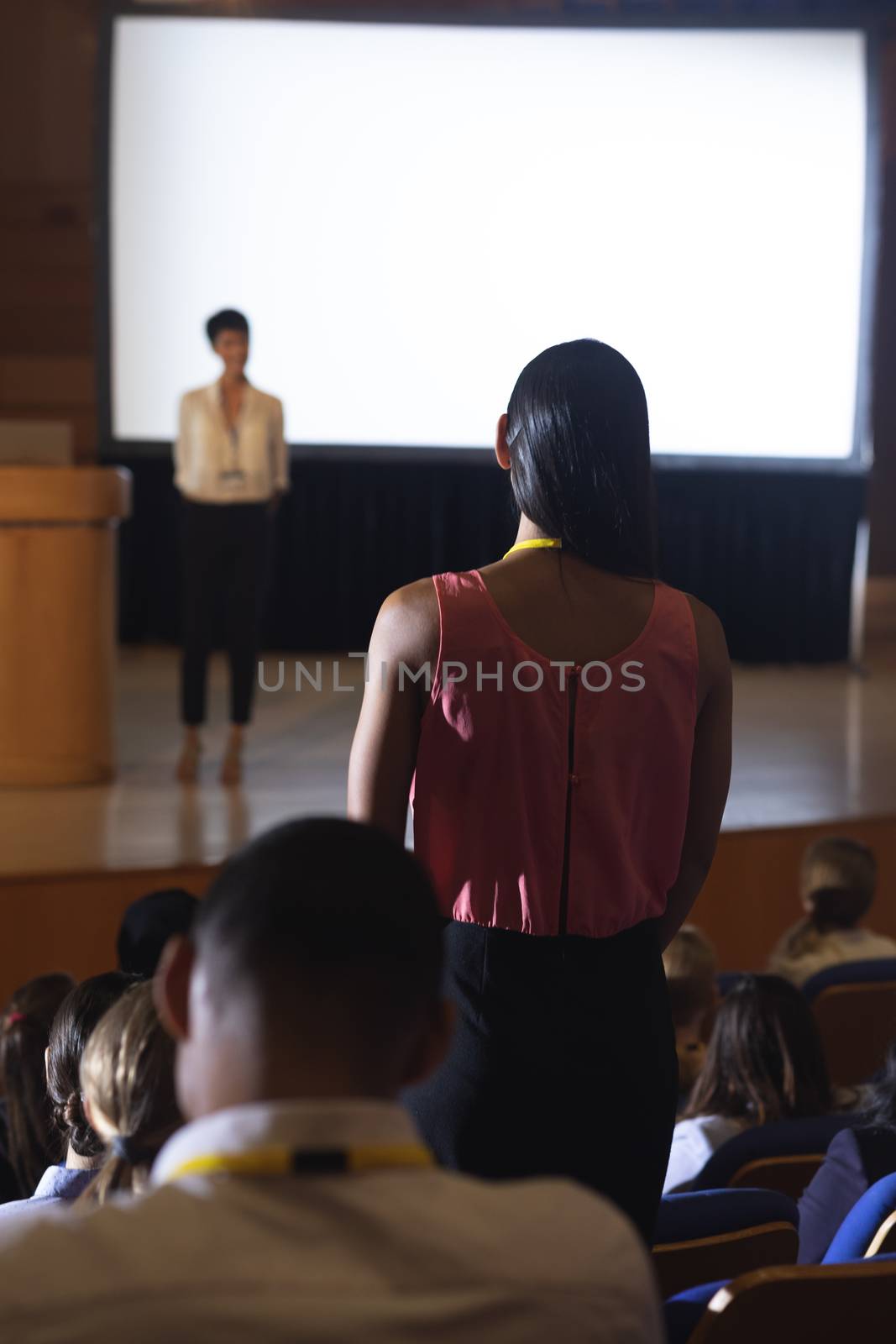 Woman from the audience standing and asking query in the auditorium  by Wavebreakmedia