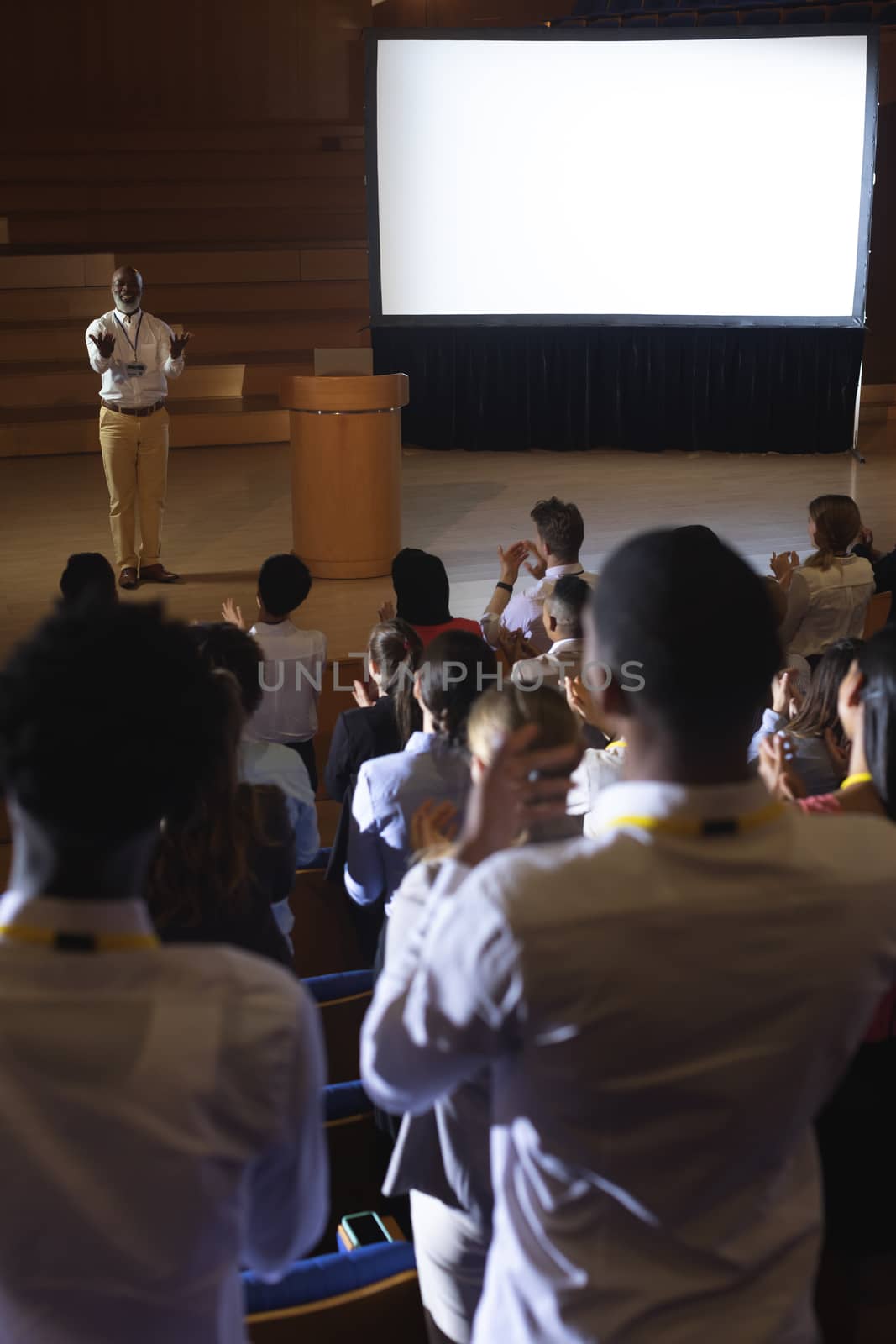 Businessman standing and giving presentation in auditorium  by Wavebreakmedia