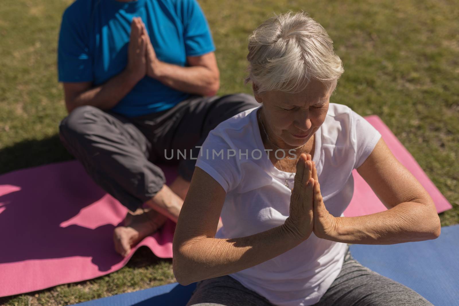 High angle view of active senior woman performing yoga on yoga mat in the park