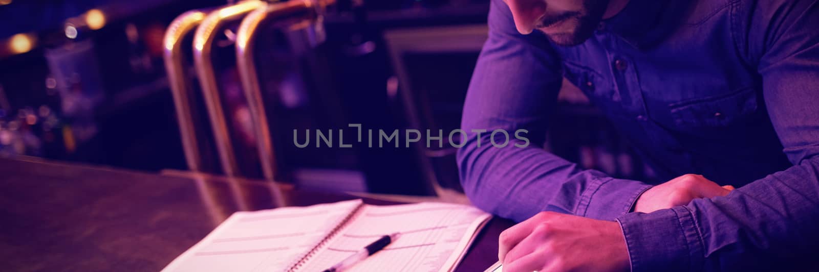 Bartender using digital tablet at bar counter by Wavebreakmedia