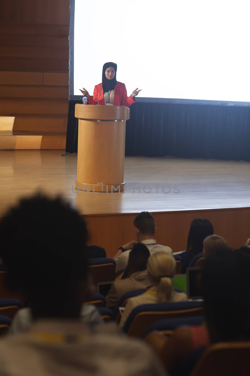 Front view of mixed race businesswoman giving speech in front of audience in the auditorium