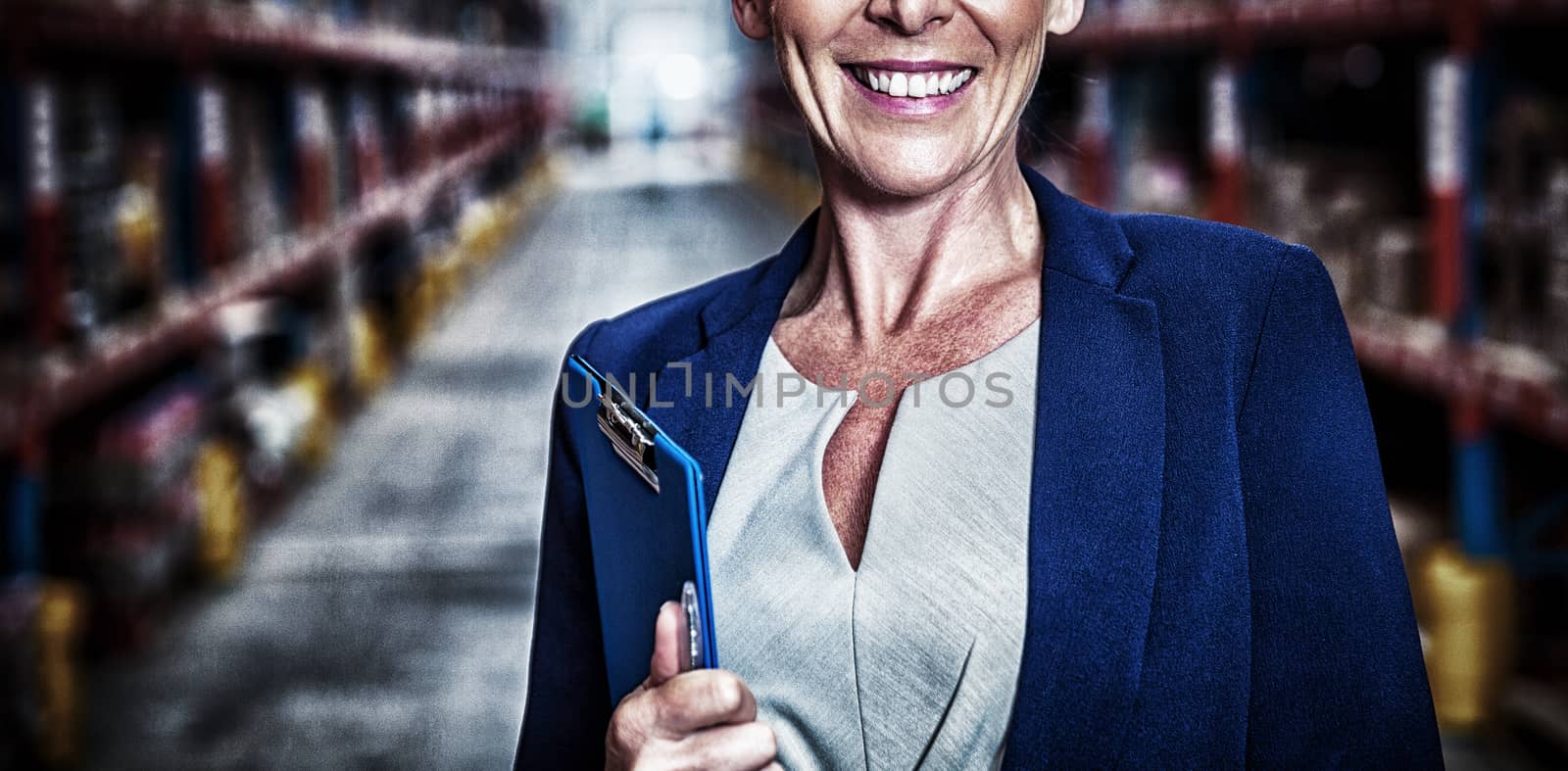 Business woman smiling with her clipboard in a warehouse 