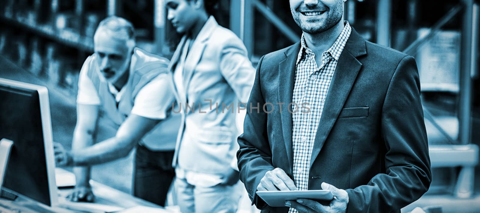 Focus on manager is smiling and holding a tablet in front of his colleagues by Wavebreakmedia