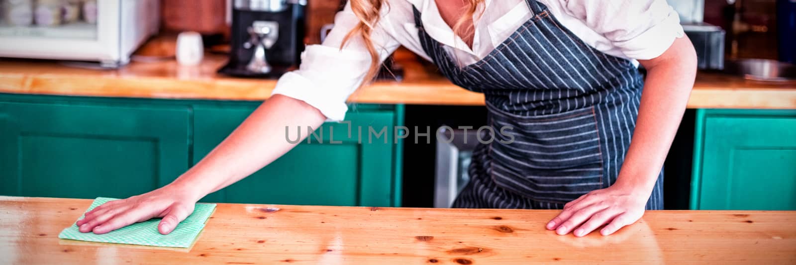 Waitress cleaning cafe counter  by Wavebreakmedia