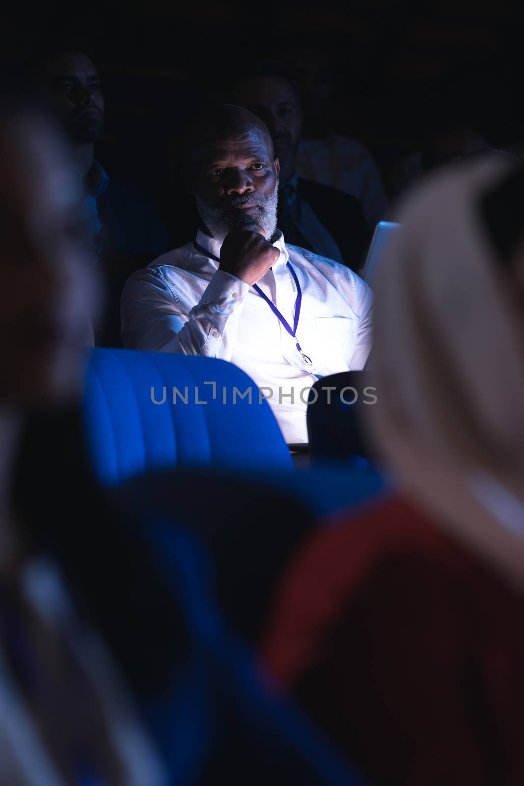 Low angle view of old African-American businessman looking and thinking while sitting in the auditorium