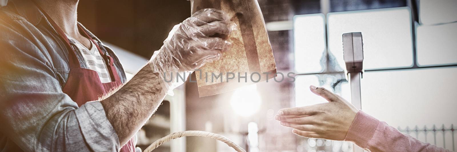 Staff giving packet bread to customer in supermarket