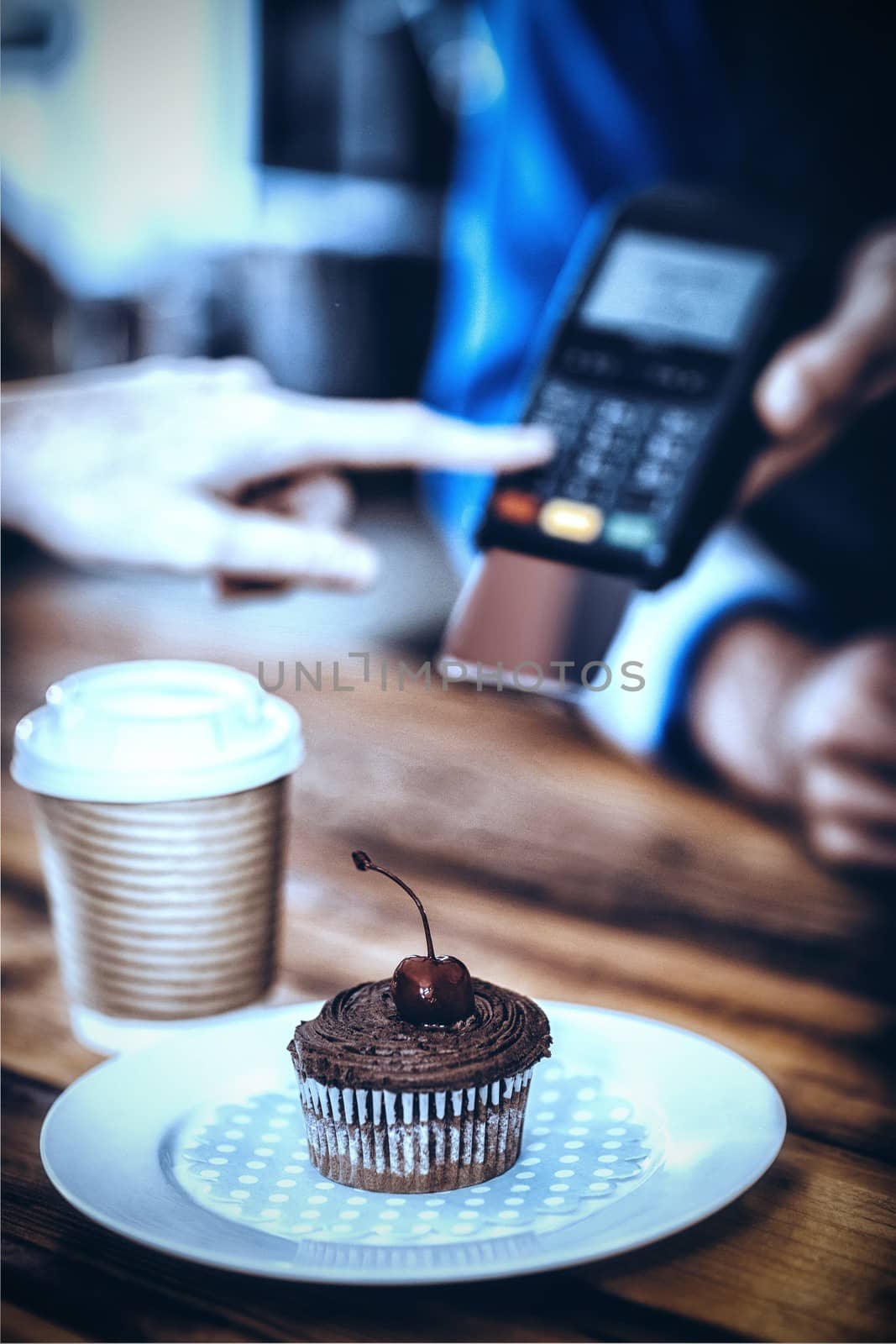 Plate of cupcake and coffee at counter in cafe by Wavebreakmedia