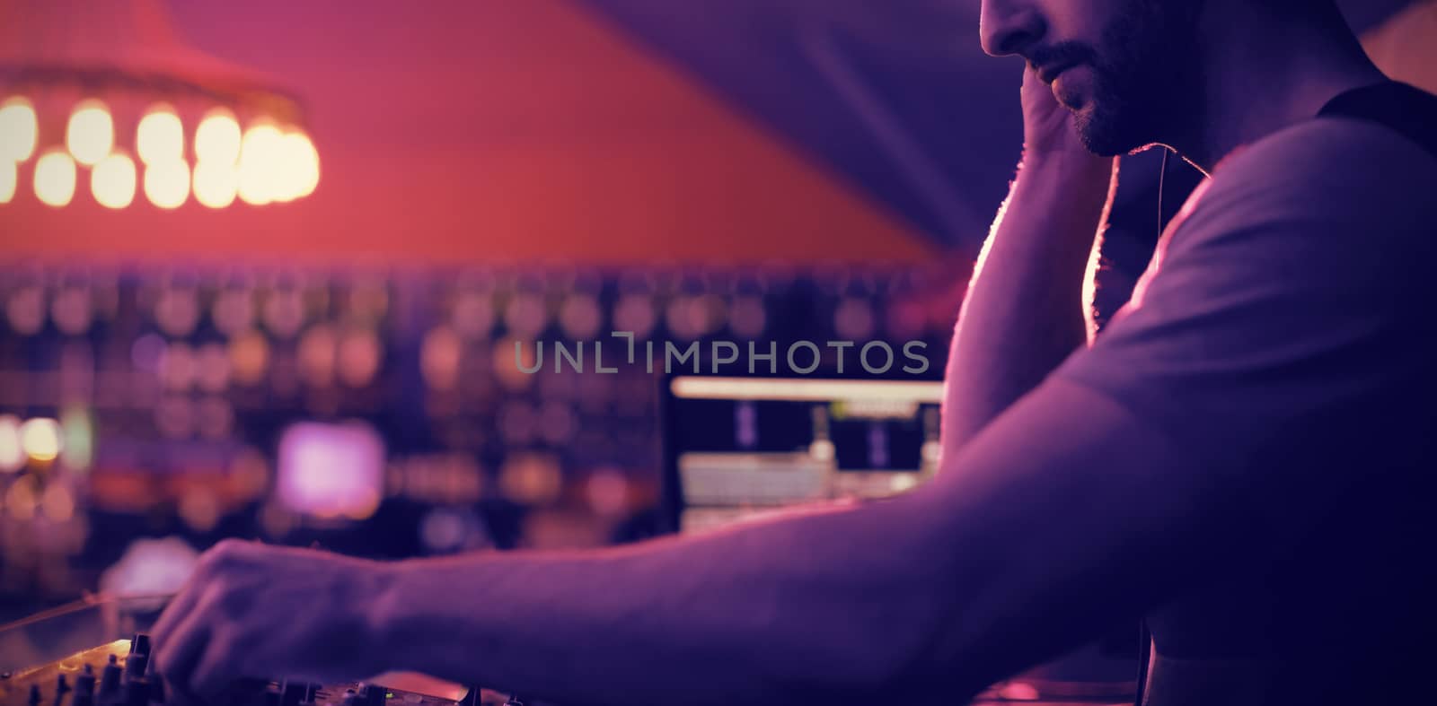 Male dj listening to headphones while playing music in bar