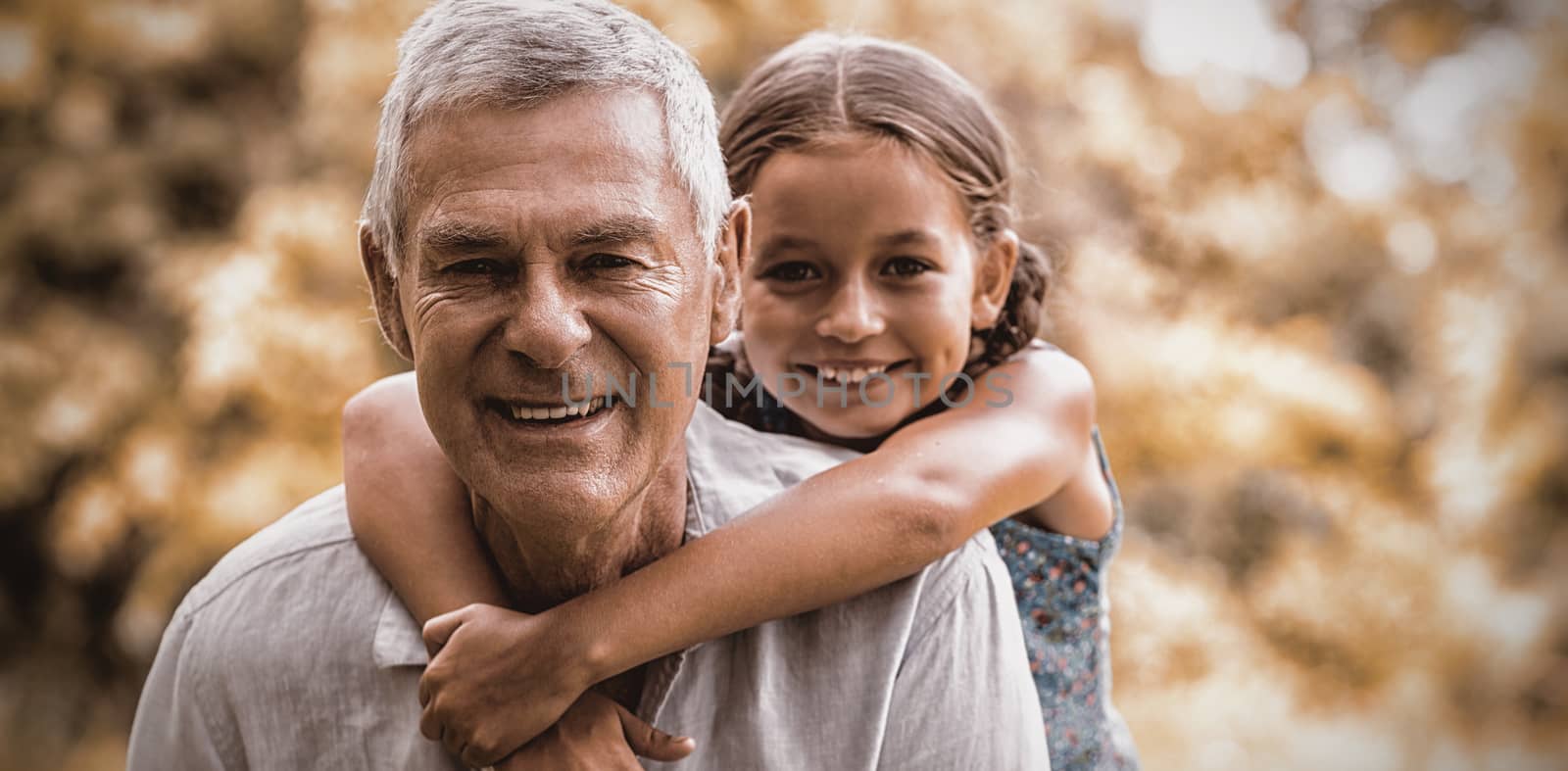 Smiling grandfather carrying grandaughter in yard 