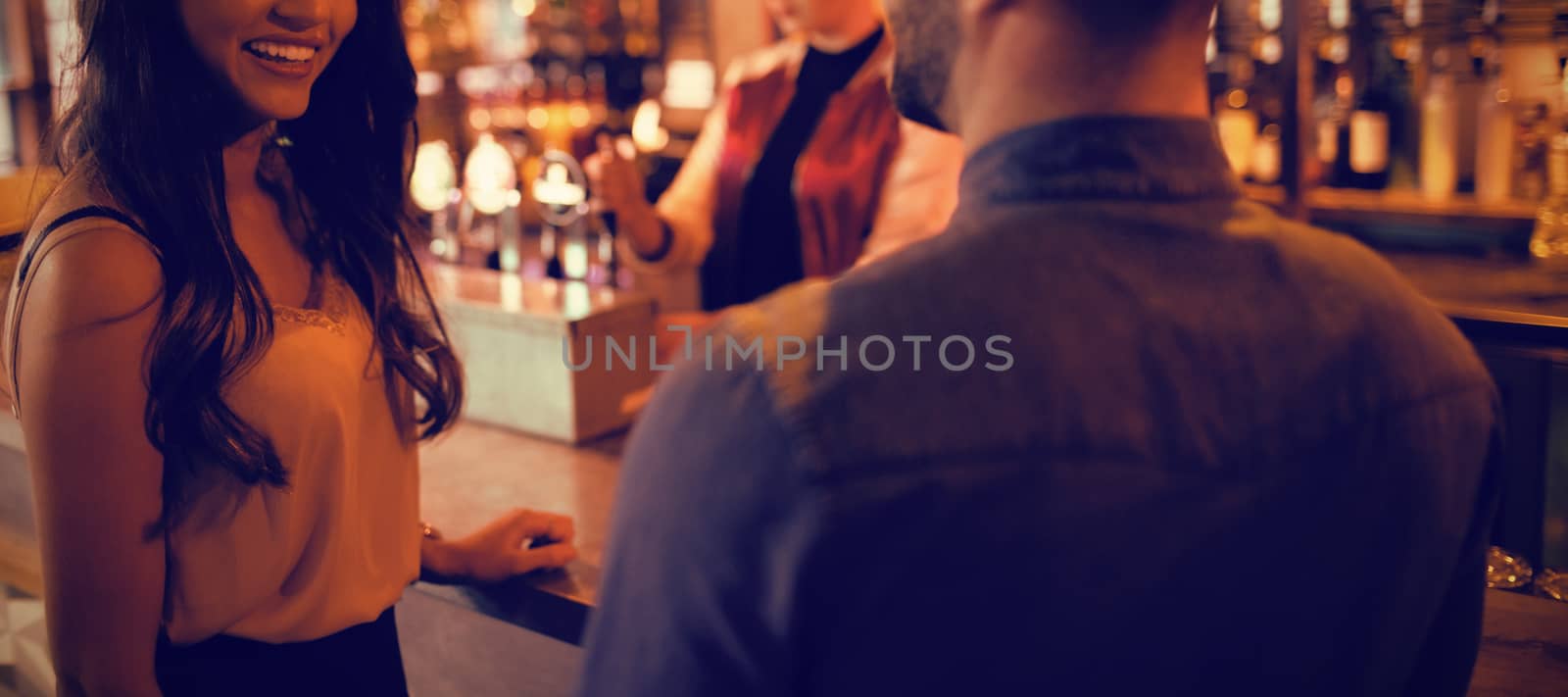 Friends interacting at counter in bar by Wavebreakmedia