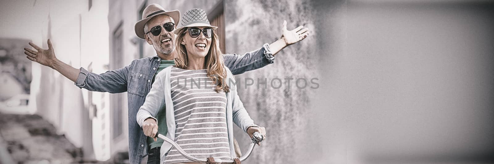 Mature couple riding bicycle by building by Wavebreakmedia