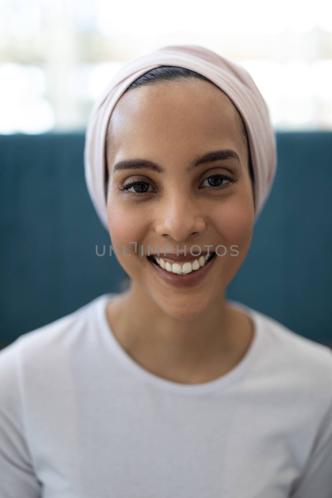 Portrait of beautiful young mixed-race female executive standing in the lobby at office. She is looking and smiling at camera