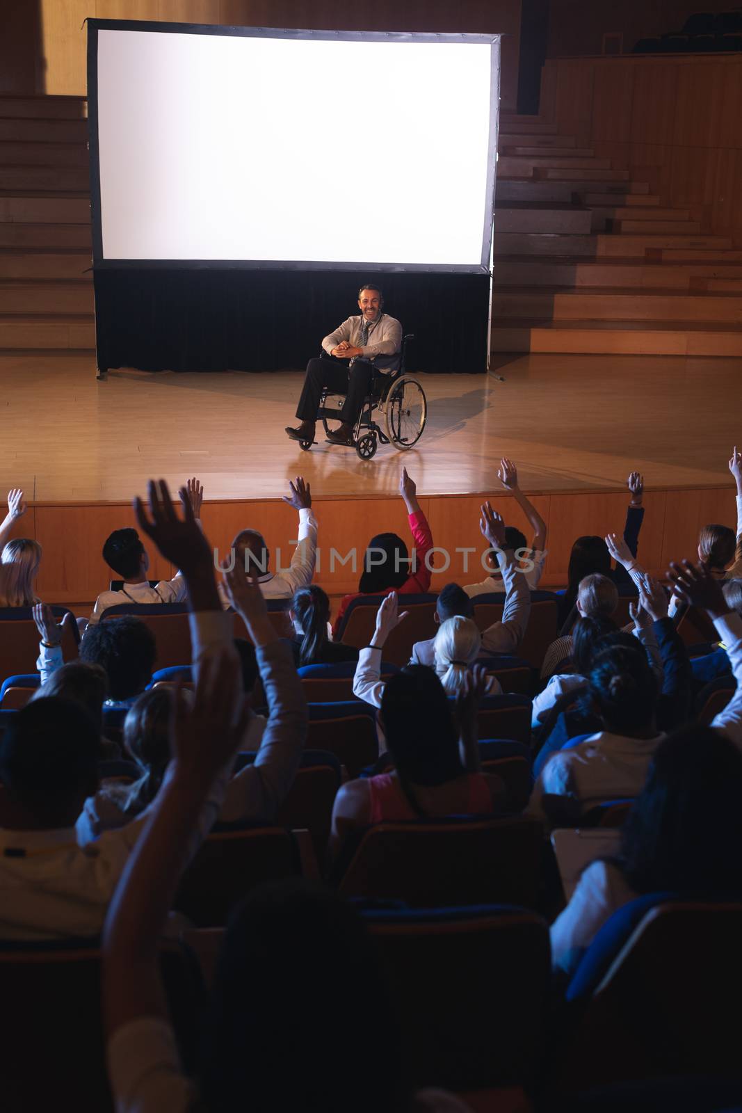 Businessman sitting on a wheelchair and giving presentation to the audience  by Wavebreakmedia