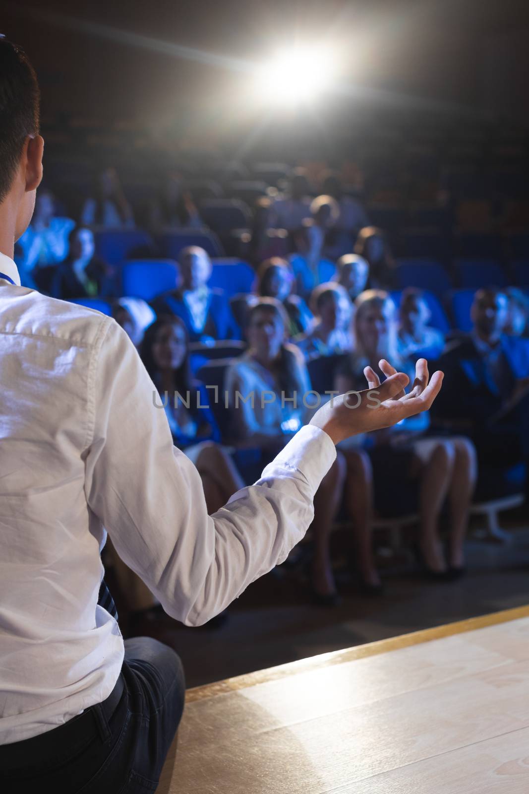 Rear view of Caucasian businessman giving presentation in front of audience in auditorium