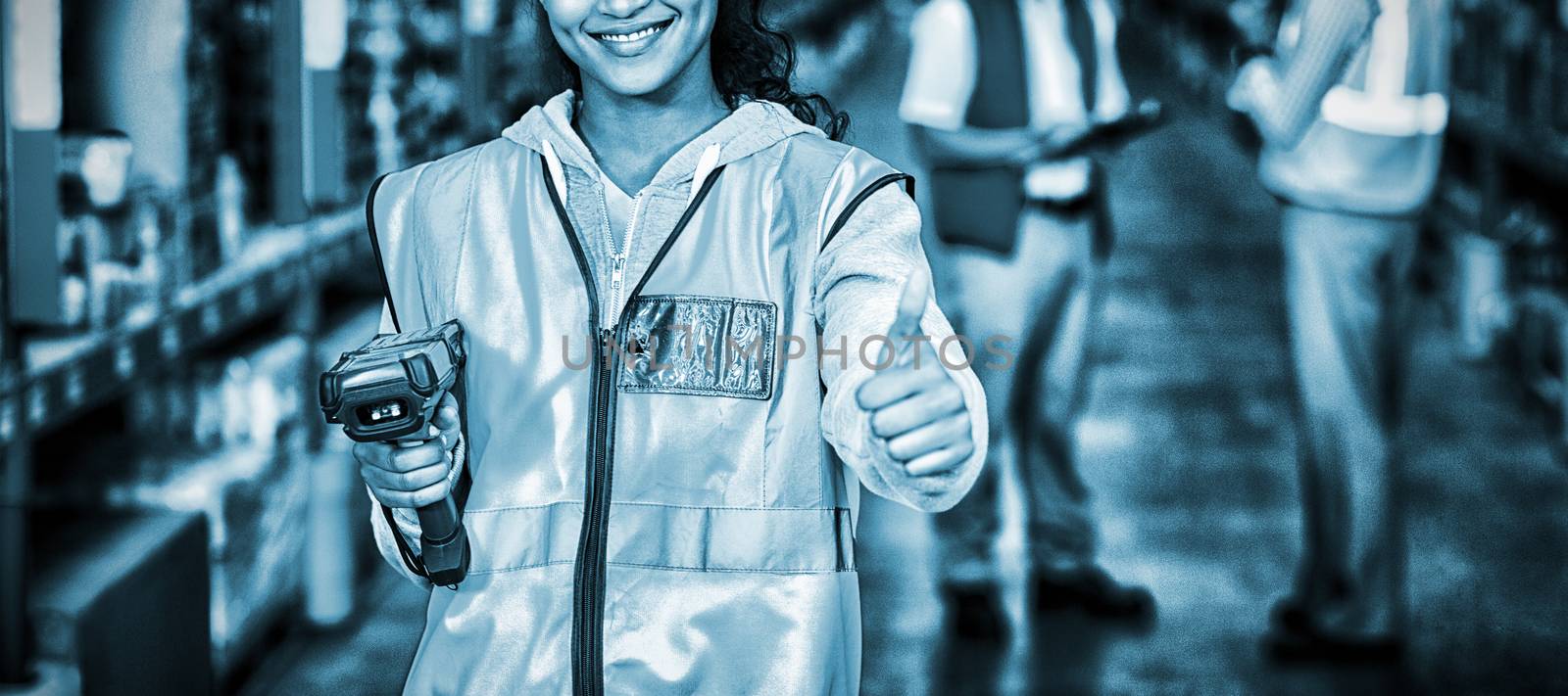 Smiling female worker with thumb up in warehouse