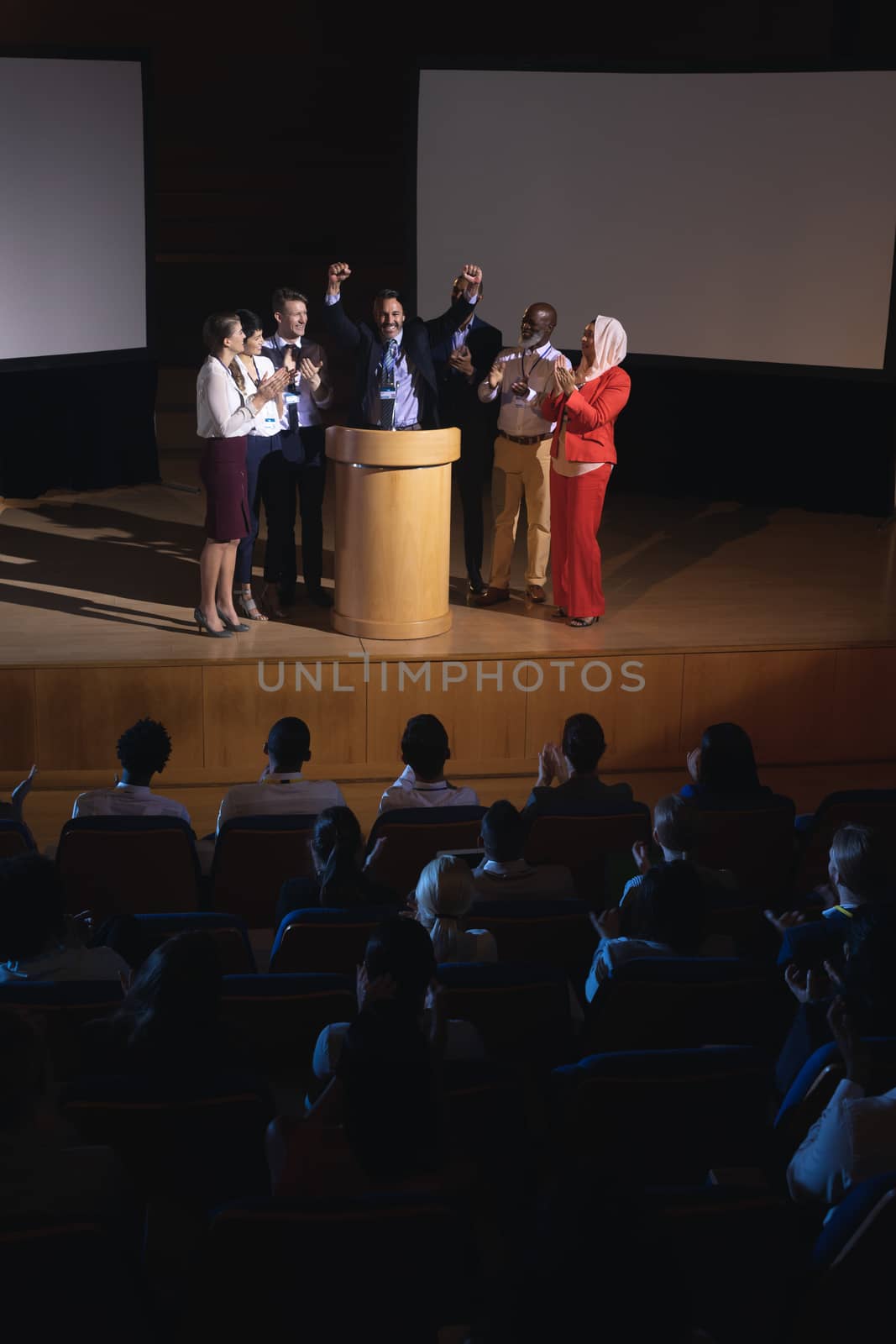 Happy businessman standing at the stage of the auditorium with colleagues  by Wavebreakmedia