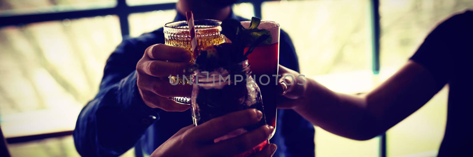 Friends toasting glasses of drinks in bar by Wavebreakmedia