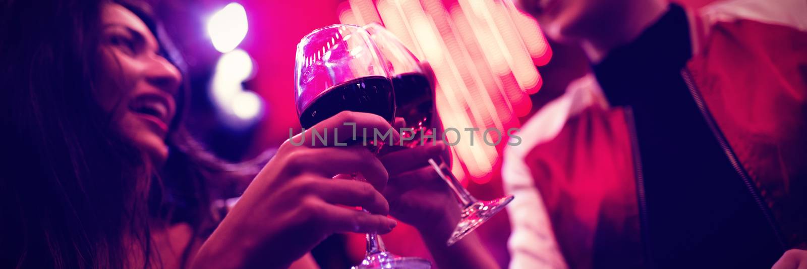 Smiling friends toasting wine glasses in bar