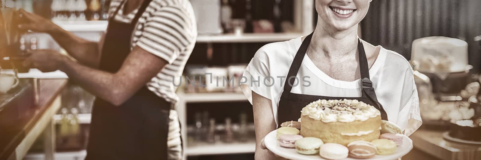 Portrait of waitress holding dessert on cake stand in cafe