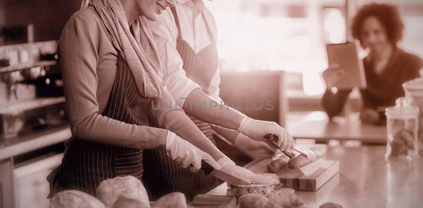 Smiling waiter and waitress working at counter in cafÃ©